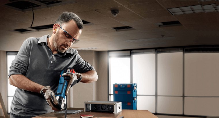 A man uses a Bosch cordless oscillating tool to plunge cut into wood